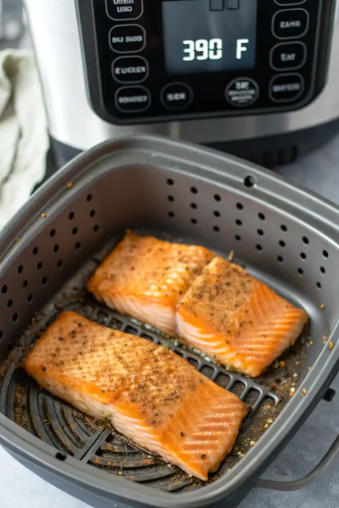 Salmon fillets cooking in an air fryer basket at 390°F.